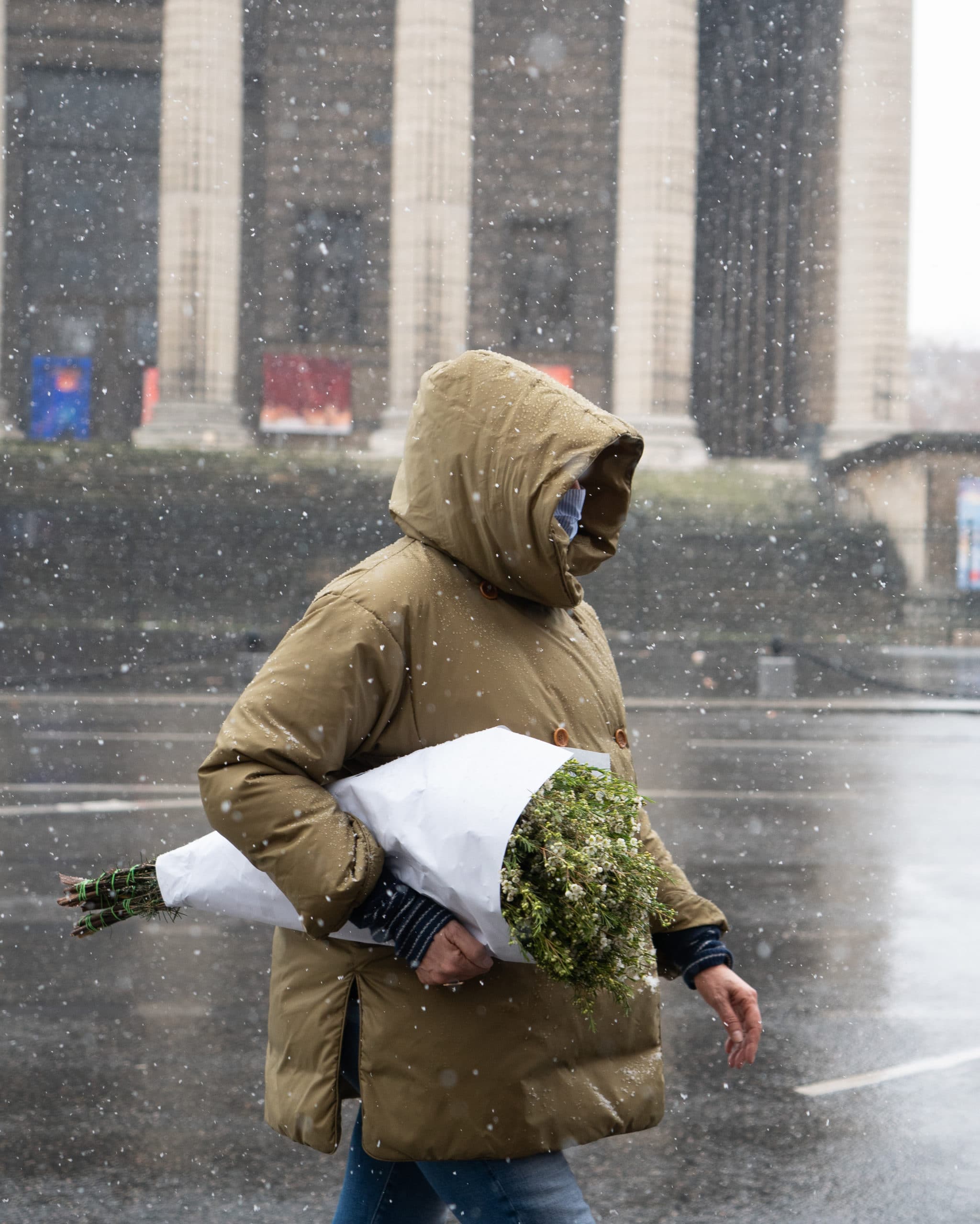 Photo de rue d'une personne portant des fleurs sous la neige à Paris
